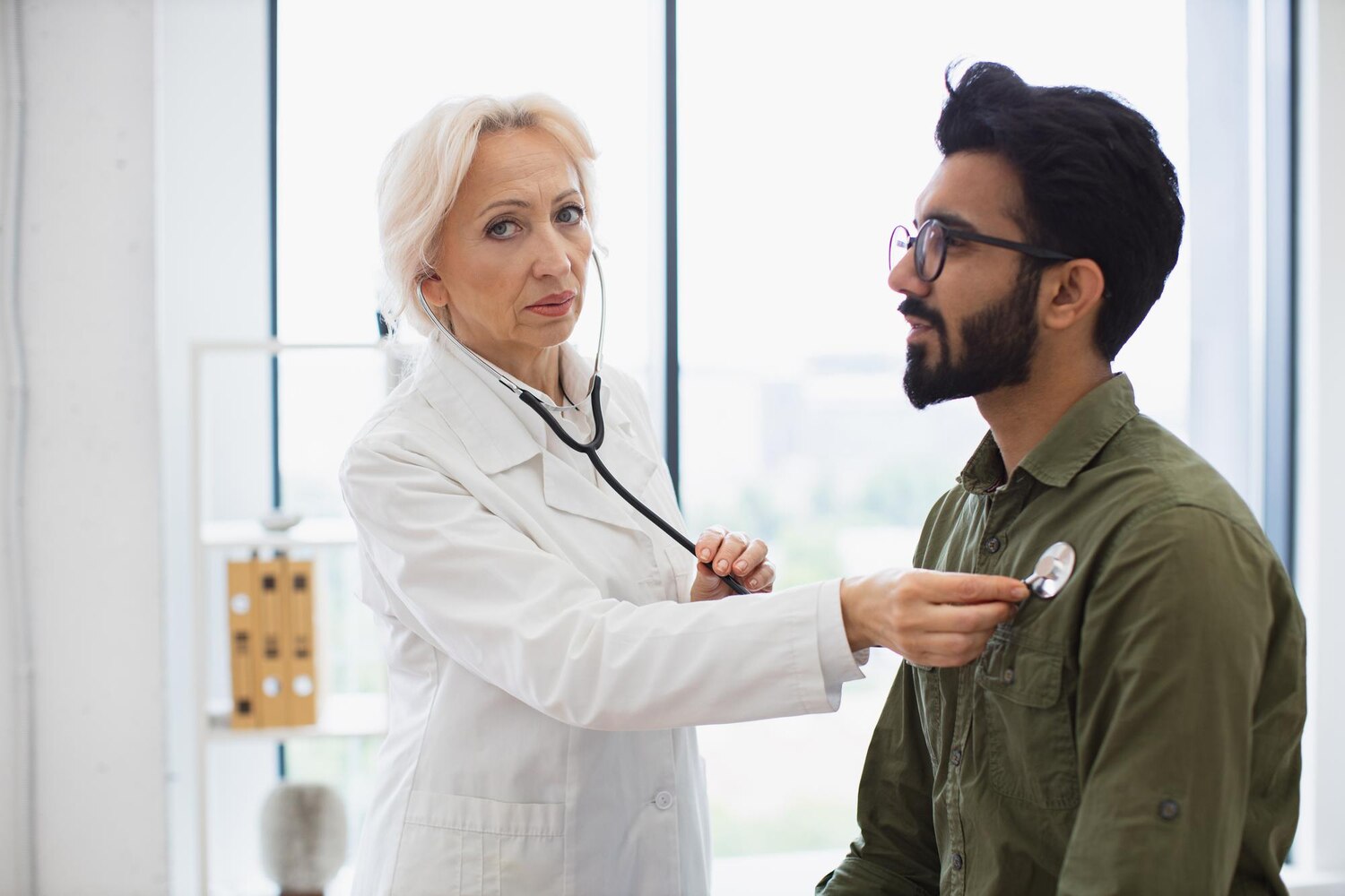 Medic care ascultă plămânii unui pacient adult pentru a evalua afectarea pulmonară
