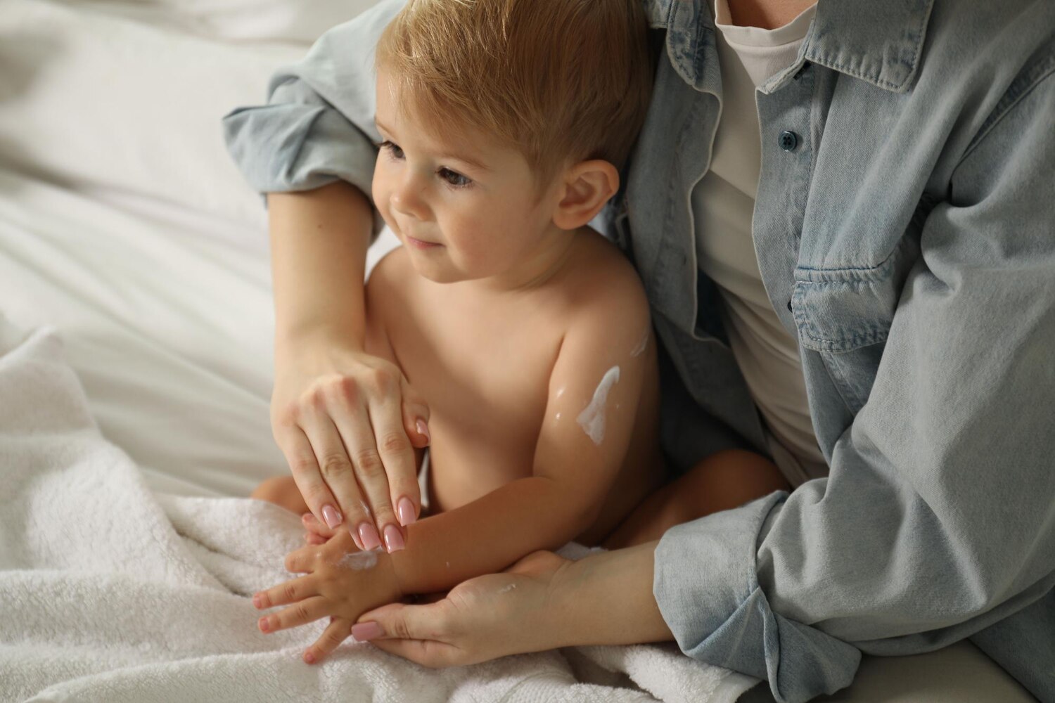 Dermatita atopica: Mamă care aplică cremă hidratantă pe brațul copilului cu dermatita atopică